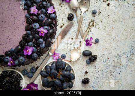 Sweet and tasty tart with fresh blueberries, blackberries and grapes, served on stone background Stock Photo