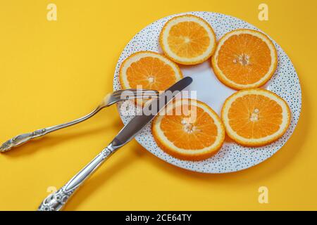 Orange slices on a plate and a knife with a fork. Diet concept Stock Photo