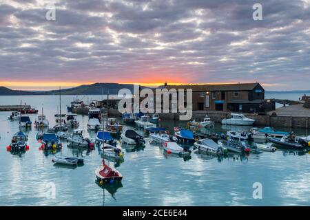 Lyme Regis, Dorset, UK.  31st August 2020.  UK Weather. The sunrise at Lyme Regis in Dorset on Bank Holiday Monday is obscured by a patchwork of cloud on a chilly morning.   Picture Credit: Graham Hunt/Alamy Live News