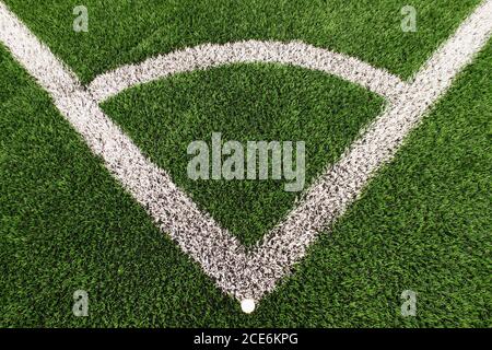 Football playground corner on artificial green turf ground with painted white line marks. Milled black rubber in basic. Stock Photo