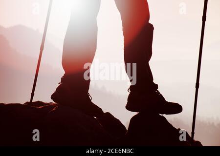 Man hiker legs in boots and poles stand on mountain Stock Photo