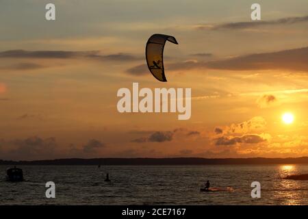 A power kite surfer swimming in the lagoon against the backdrop of a sunset, Lithuania Stock Photo