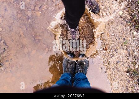 From above of couple of tourists having fun and playing in mud puddle while making splashes Stock Photo