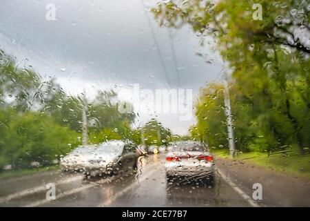raindrops on the windshield of a car that is moving, driving on a country road in rainy weather Stock Photo
