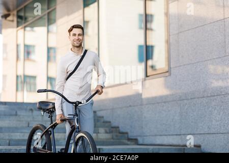 Convenient transport in city. Businessman walking down stairs with bicycle Stock Photo