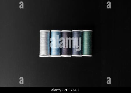 Kit of colorful reels of threads in atelier on black background Stock Photo