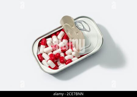 From above of metal container with pile of capsules placed on white table in studio Stock Photo