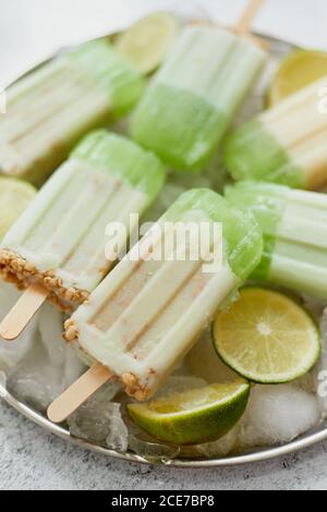 Summer refreshing homemade lime popsicles with chipped ice over stone background Stock Photo