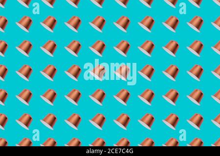 Top view of golden coffee pods placed in even rows as seamless pattern on blue background Stock Photo