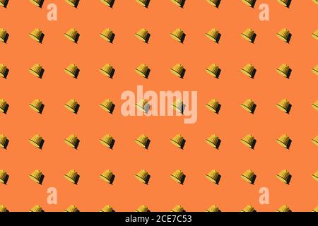 Top view of yellow coffee pods placed in even rows as seamless pattern on orange background Stock Photo