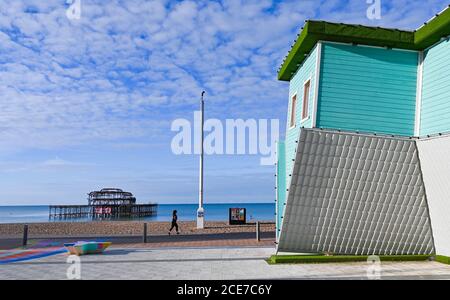 Brighton UK 31st August 2020 - A runner passes by the Upside Down House on Brighton seafront on a beautiful sunny morning to begin the August Bank Holiday Monday . The forecast is for it be much cooler than normal in some parts of Britain today : Credit Simon Dack / Alamy Live News Stock Photo