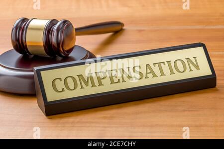 A gavel and a name plate with the engraving Compensation Stock Photo