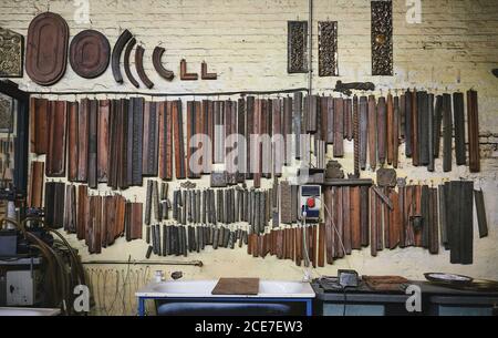 Set of various metal tools and details arranged on weathered wall near workbench in goldsmith workshop Stock Photo