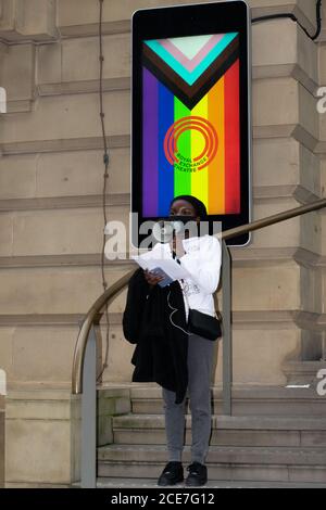 Extinction rebellion protest outside the Royal Exchange Theatre, Manchester, UK and woman with megaphone in front of pride symbol Stock Photo