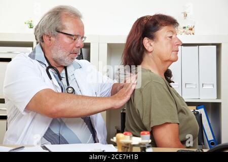 Doctor treats an elderly patient with back pain in his practice Stock Photo
