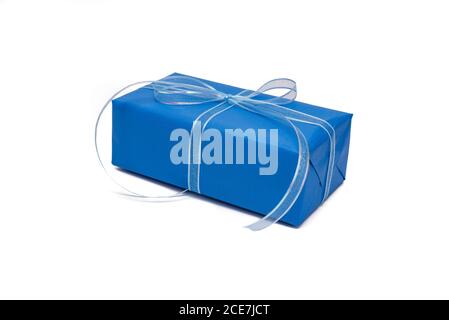 Gift box wrapped in trendy blue paper on white background. Classic blue color. Festive composition in minimal style. Holiday concept. Mockup Stock Photo