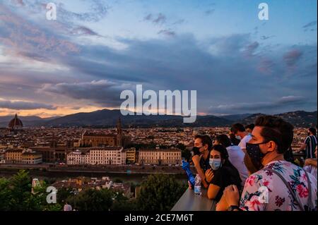 Florence, Italy. 30th Aug, 2020. People crowd on to the terrace and steps of the Piazzale Michelangelo for a panoramic view of the city as the sun sets, some wear masks, some don't - Visitors return to see the varied sights of the historic city of Florence following the easing of Coronavirus (covid 19) travel restrictions. Credit: Guy Bell/Alamy Live News Stock Photo