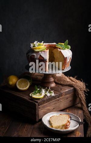 Side view still life of lime and lemon sponge served on a wooden pedestal and slice piece on a plate below Stock Photo