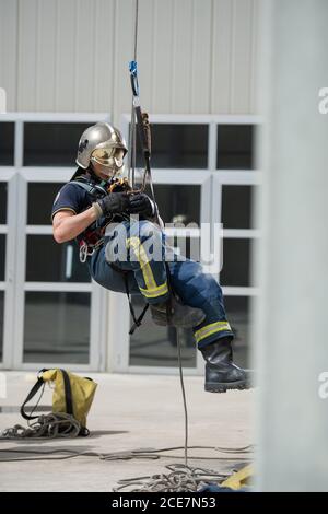 Side view of strong firefighter in protective equipment during training  with ropes near building on background of blue sky Stock Photo - Alamy