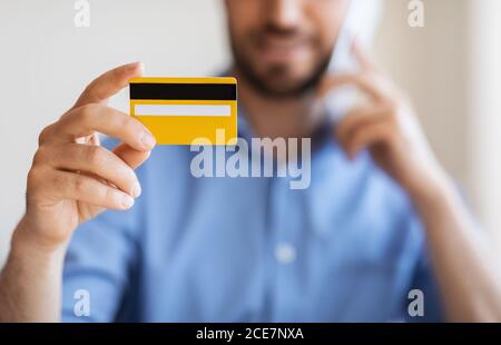 Online Banking. Unrecognizable Man Holding Credit Card And Talking On Cellphone Stock Photo