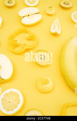Top view of various fresh fruits and vegetables arranged on yellow background Stock Photo