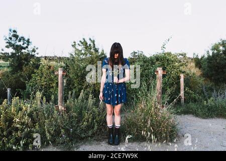 anonymous female in summer dress standing in countryside with scissors and bunch of fresh wildflowers Stock Photo