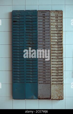 Rusty metal mailboxes placed on tiled wall of weathered abandoned building during daytime Stock Photo