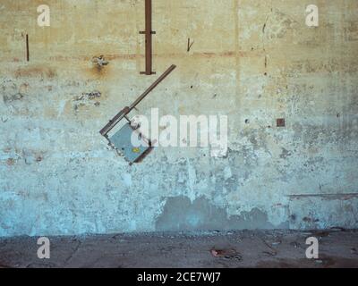 Broken power supply box hanging on weathered wall in facility of abandoned plant Stock Photo