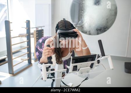 Woman wearing VR glasses doing exercises in a gym Stock Photo