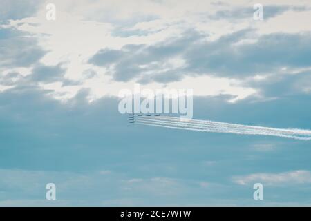 Row of planes flying in the sky with a trail of colorful smoke