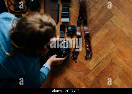 From above anonymous Woman placing photography equipment on shabby parquet floor at home Stock Photo