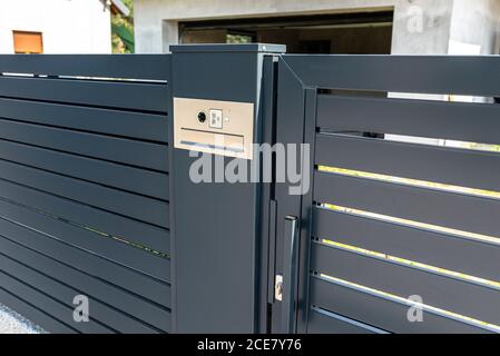 A modern videophone with a letterbox and a wireless card reader, mounted in panel fence in anthracite color, visible wicket. Stock Photo