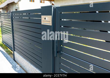 A modern videophone with a letterbox and a wireless card reader, mounted in panel fence in anthracite color, visible wicket. Stock Photo