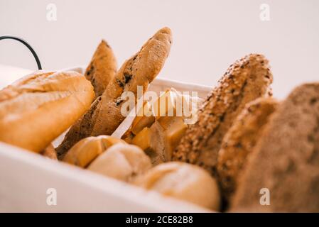 Fresh assorted cut bread and buns served in tray on white table during breakfast Stock Photo