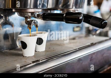Professional coffee machine pouring coffee into small ceramic cups in coffeehouse with contemporary equipment Stock Photo
