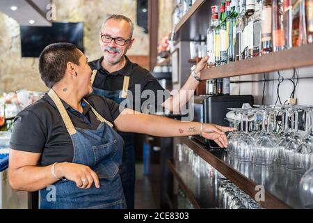 Side view of male and female bar coworkers making drinks while talking to each other during working day Stock Photo