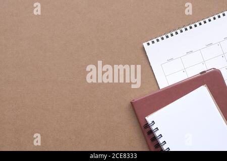 Notepads and calendar on brown color desk. Top view. Copy space. Stock Photo