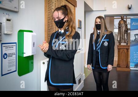 (left to right) Sarah Watt and Leah McCallum, S4 students at St Columba's High School, Gourock, disinfect their hands and put on their protective face masks as the requirement for secondary school pupils to wear face coverings when moving around school comes into effect from today across Scotland. Stock Photo