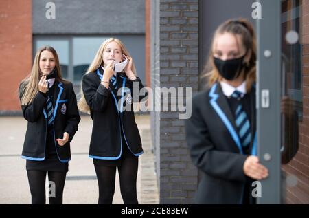 (left to right) Leah McCallum, Rebecca Ross and Sarah Watt, S4 students at St Columba's High School, Gourock, put on their protective face masks as the requirement for secondary school pupils to wear face coverings when moving around school comes into effect from today across Scotland. Stock Photo