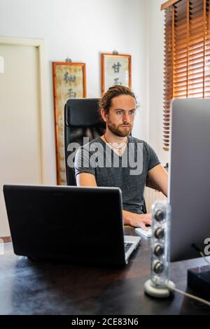 Handsome man working at desktop computer at home Stock Photo