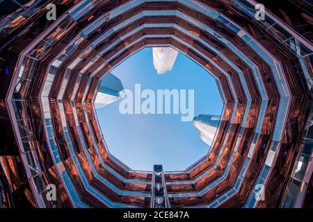 Modern skyscrapers seen from inside of Vessel artwork against blue sky in Hudson Yards in New York City Stock Photo
