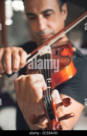 Talented focused Hispanic male violinist playing violin during rehearsal Stock Photo