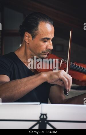 Talented focused Hispanic male violinist playing violin during rehearsal Stock Photo