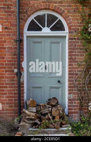 Chopped logs ready to be put on a fire stacked up at the back door of an english cottage Stock Photo