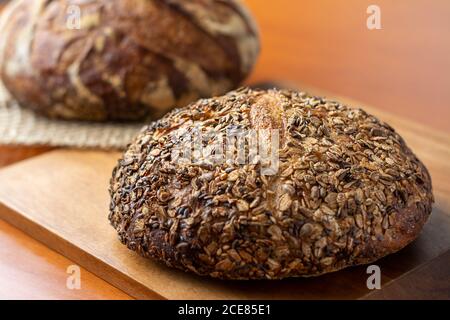 An artisan bread loaf with seeds on wooden background