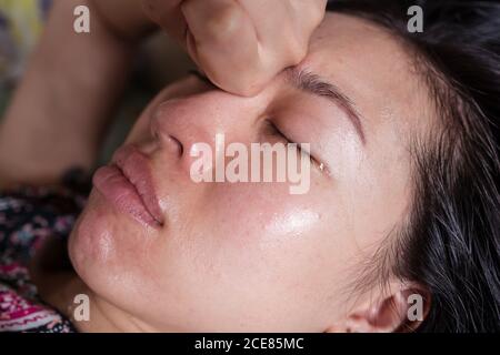 Sick ethnic female lying on bed and crying while having flu and headache Stock Photo