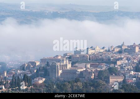 Amazing cityscape with aged stone buildings located on hill on background of cloudy foggy sky Stock Photo