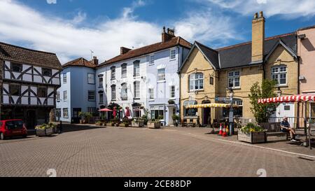 Sun shines on the traditional shop and pub buildings of The Square market place in Axbridge, Somerset. Stock Photo