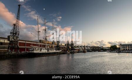 Evening light shines on the M Shed museum, historic vessels and modern apartment buildings on Bristol's regenerated post-industrial Harbourside. Stock Photo