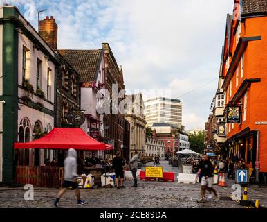 People sit at benches in the street for al fresco dining and drinking outside the bars and restaurants of Bristol's historic King Street during the Cov Stock Photo